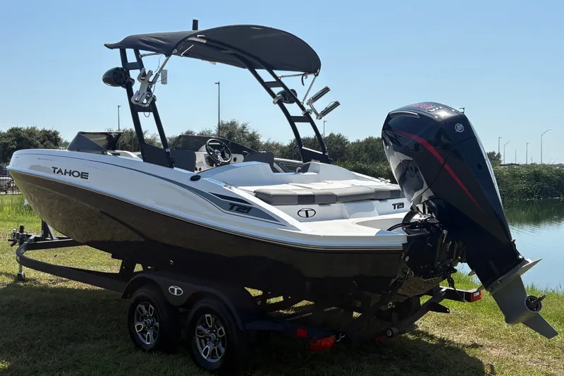 The Image of A modern 2026 Tahoe T21 sits on a trailer beside a body of water. - 1