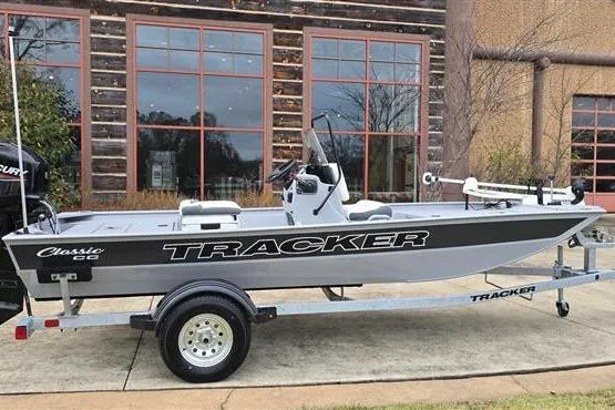 Slide: The Image of 2026 Tracker Bass Tracker Classic CC boat on trailer, parked outside a rustic building. - 2