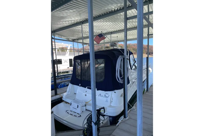 Slide: The Image of 2005 Sea Ray Sundancer 320 docked under a covered marina with an American flag. - 2