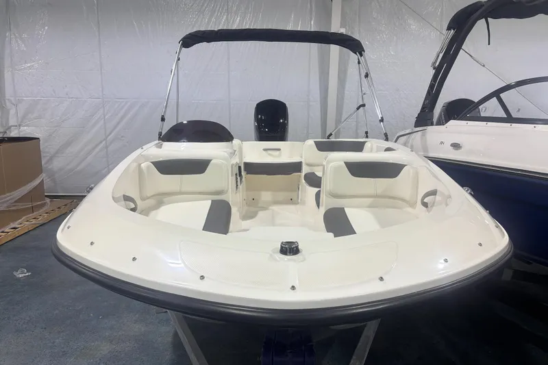 Slide: The Image of 2025 Bayliner Element E16 boat with white seating and canopy in a showroom. - 2
