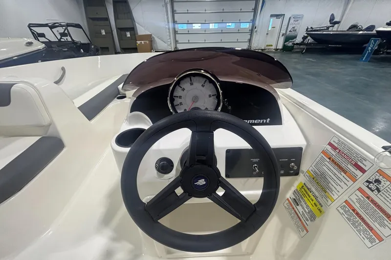 Slide: The Image of 2025 Bayliner Element E16 boat dashboard with steering wheel and gauges in a showroom. - 3