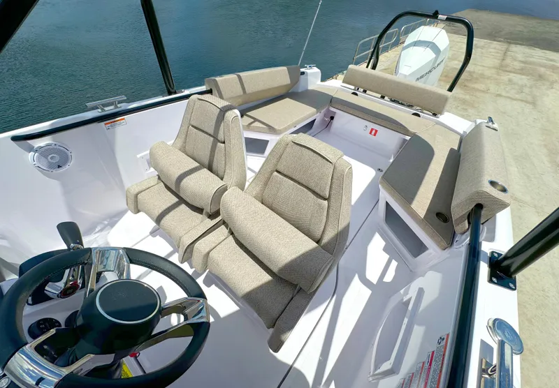 Slide: The Image of 2024 Axopar 25 Cross Top boat interior with beige seating and steering wheel. - 10