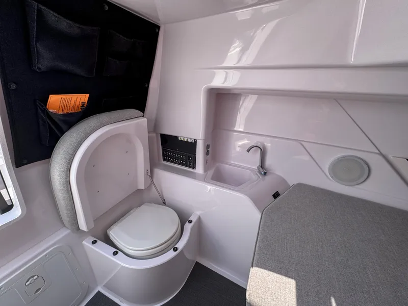 Slide: The Image of 2024 Axopar 25 Cross Top interior with toilet, sink, and seating area. - 12