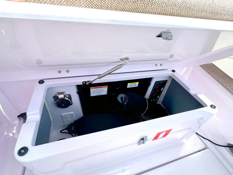 Slide: The Image of 2024 Axopar 25 Cross Top storage compartment with open lid, showcasing interior features. - 5