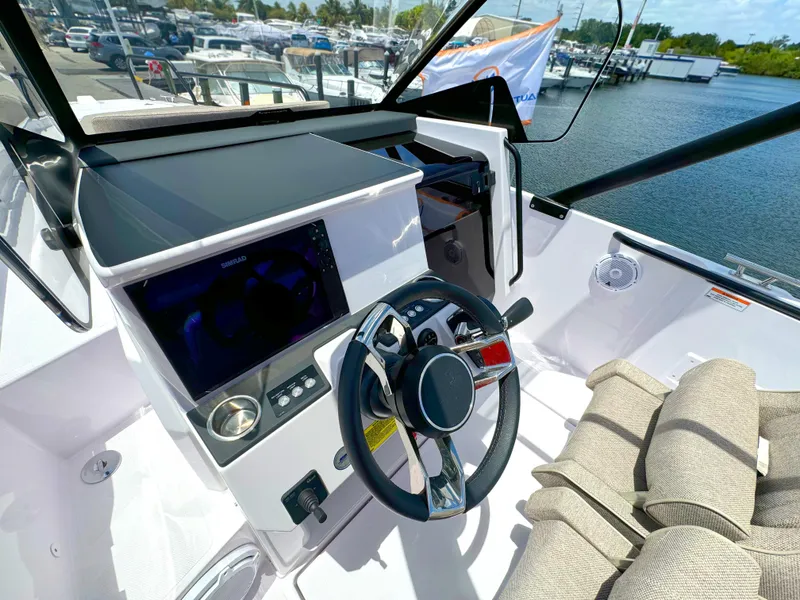 Slide: The Image of 2024 Axopar 25 Cross Top boat cockpit with steering wheel and navigation display. - 8