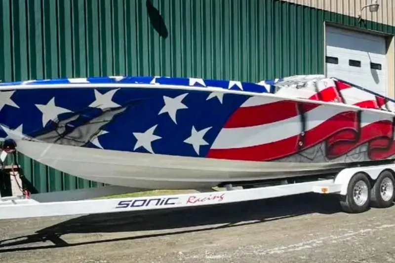 The Image of 2001 Sonic 31 SS boat with American flag design on trailer. - 1