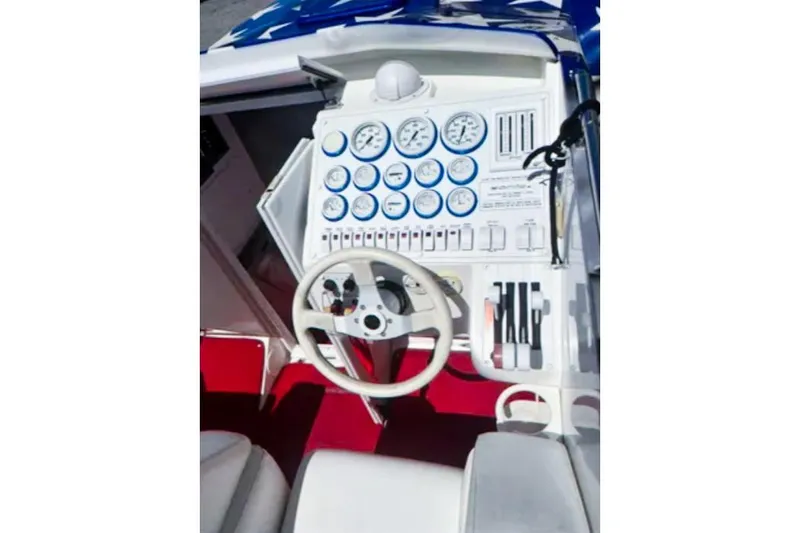 Slide: The Image of 2001 Sonic 31 SS boat dashboard with gauges and steering wheel, featuring red carpet. - 6
