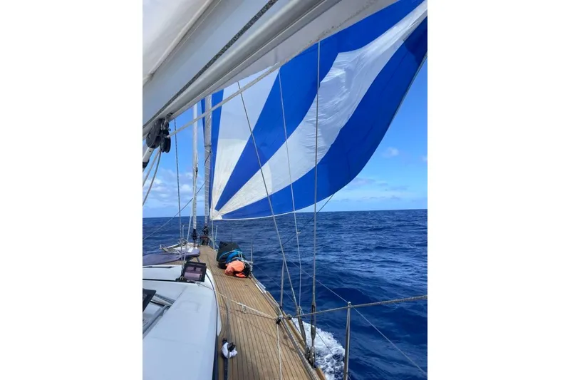 Slide: The Image of Sailing on a 2015 Beneteau Sense 55 with blue and white sails over open ocean. - 2