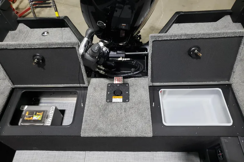 Slide: The Image of 2026 Alumacraft Competitor 185X Tiller boat interior with storage compartments and motor. - 10