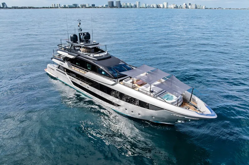 Slide: The Image of Luxury 2024 Riva 130' Bellissima yacht cruising on open water near city skyline. - 4