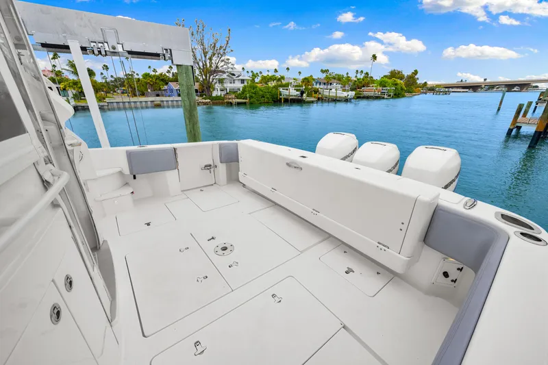 Slide: The Image of 2019 Intrepid 410 Evolution boat deck with outboard motors, docked by a scenic waterfront. - 24