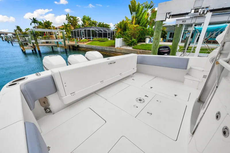 Slide: The Image of 2019 Intrepid 410 Evolution boat deck with seating, docked by waterfront homes. - 25