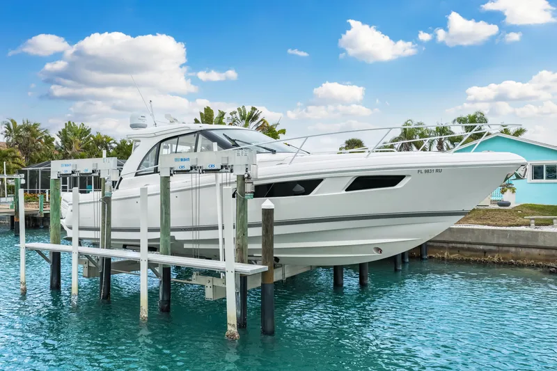 Slide: The Image of 2019 Intrepid 410 Evolution yacht on lift, docked by turquoise water, under blue sky. - 4