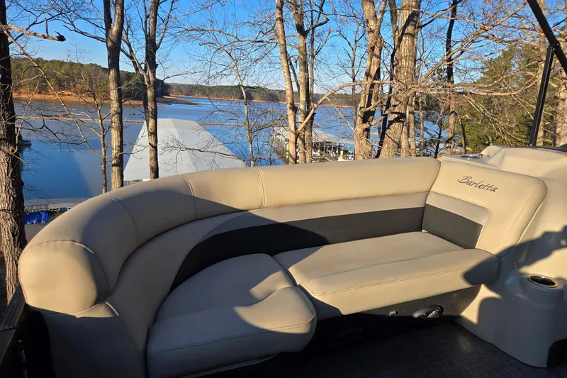 Slide: The Image of 2020 Barletta C22UC boat with beige seating, overlooking a serene lake and wooded area. - 18