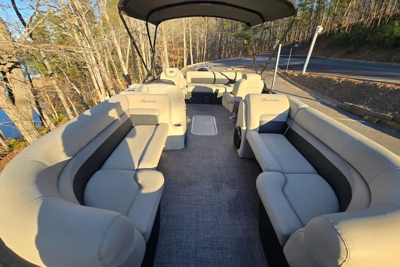Slide: The Image of 2020 Barletta C22UC pontoon boat with spacious seating and canopy, parked near a wooded area. - 8