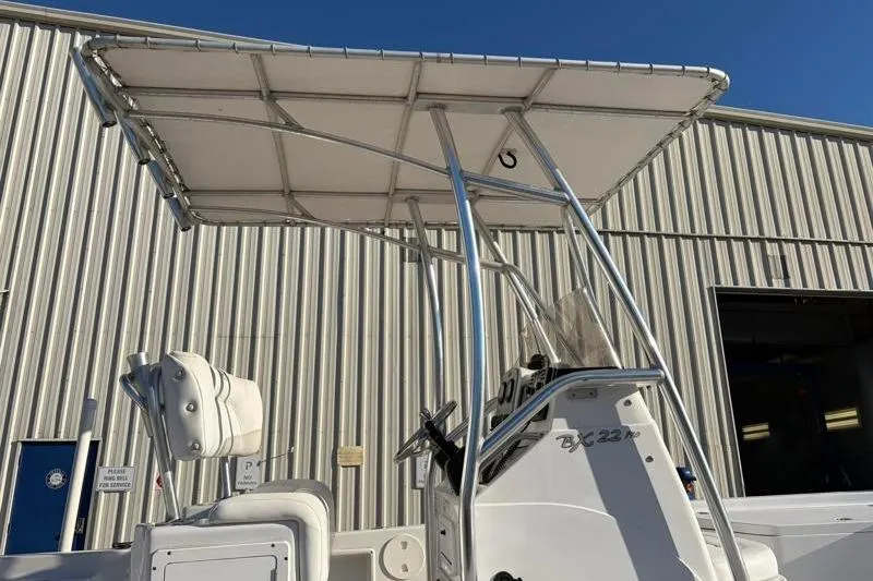 Slide: The Image of 2011 Sea Hunt BX 22 BR boat with T-top, parked near a metal building. - 15