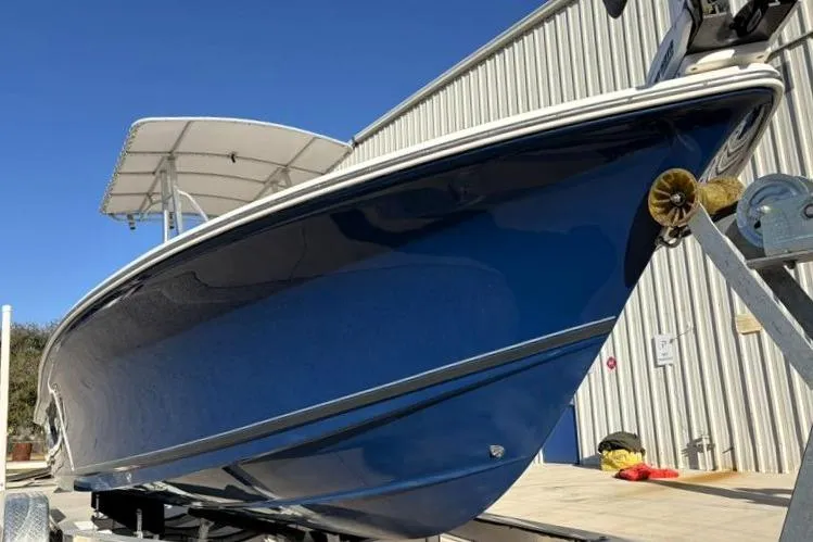 Slide: The Image of 2011 Sea Hunt BX 22 BR boat with blue hull on trailer, near metal building. - 8