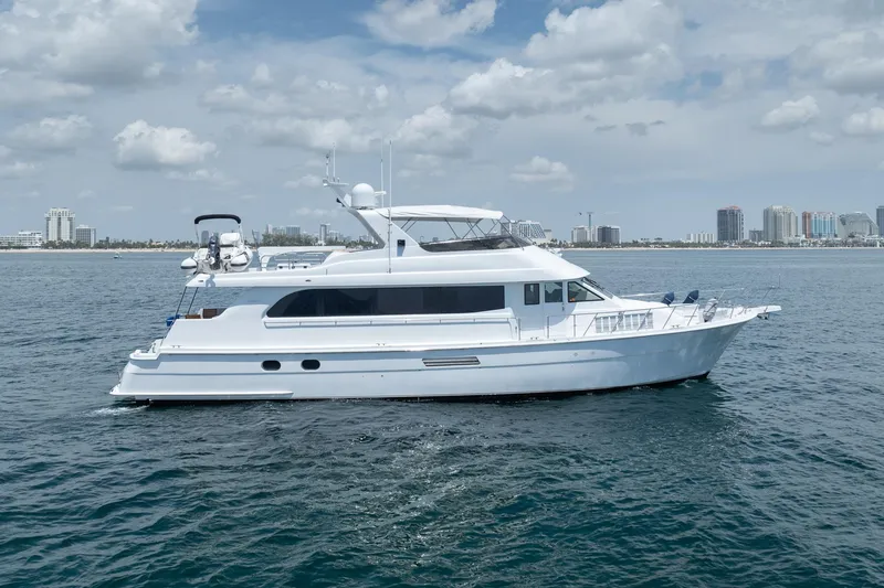 The Image of 2000 Hatteras 75 Sport Deck Motor Yacht cruising on open water under a cloudy sky. - 1
