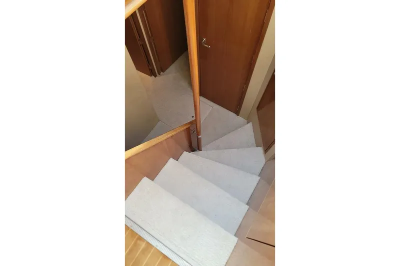 Slide: The Image of Staircase inside 2000 Hatteras 75 Sport Deck Motor Yacht, featuring wooden railings and carpeted steps. - 9