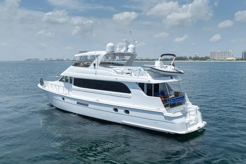 Slide: The Image of 2000 Hatteras 75 Sport Deck Motor Yacht cruising on open water under a cloudy sky. - 6