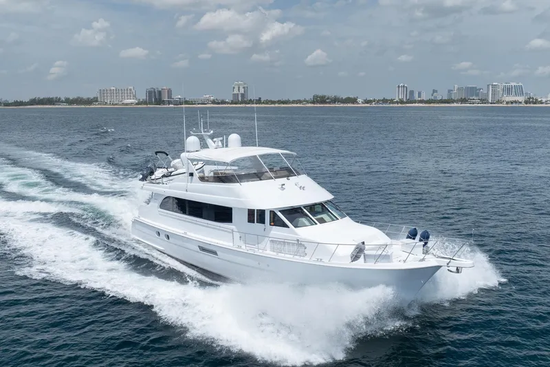 Slide: The Image of 2000 Hatteras 75 Sport Deck Motor Yacht cruising on open water near city skyline. - 9