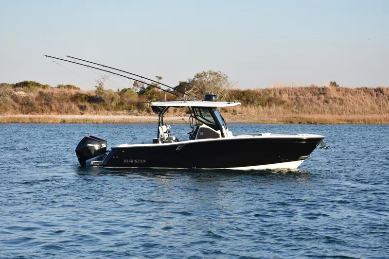 The Image of 2022 Blackfin 272 CC boat on calm water, equipped with fishing rods. - 1