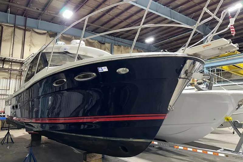 Slide: The Image of 2017 Cutwater C-302 Coupe boat in indoor storage, showcasing sleek design and sturdy build. - 2