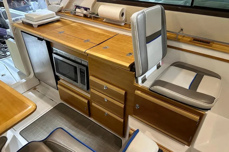 Slide: The Image of 2017 Cutwater C-302 Coupe interior with wood cabinetry, microwave, and cushioned seating. - 28