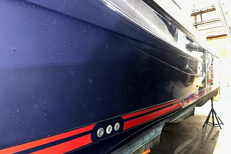 Slide: The Image of 2017 Cutwater C-302 Coupe boat hull with blue and red detailing in a workshop. - 5