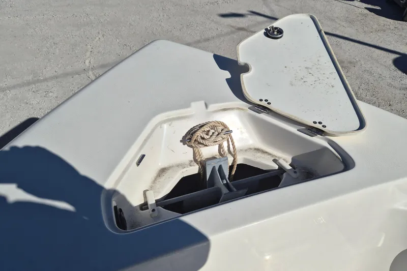Slide: The Image of 2022 Key West 203 FS boat anchor storage compartment with open lid and rope. - 12