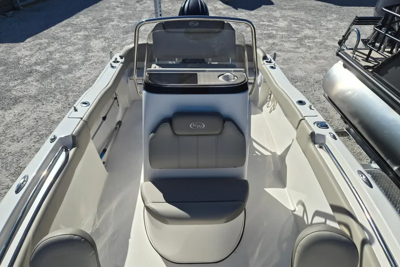 Slide: The Image of 2022 Key West 203 FS boat interior with seating and console, parked on gravel. - 9