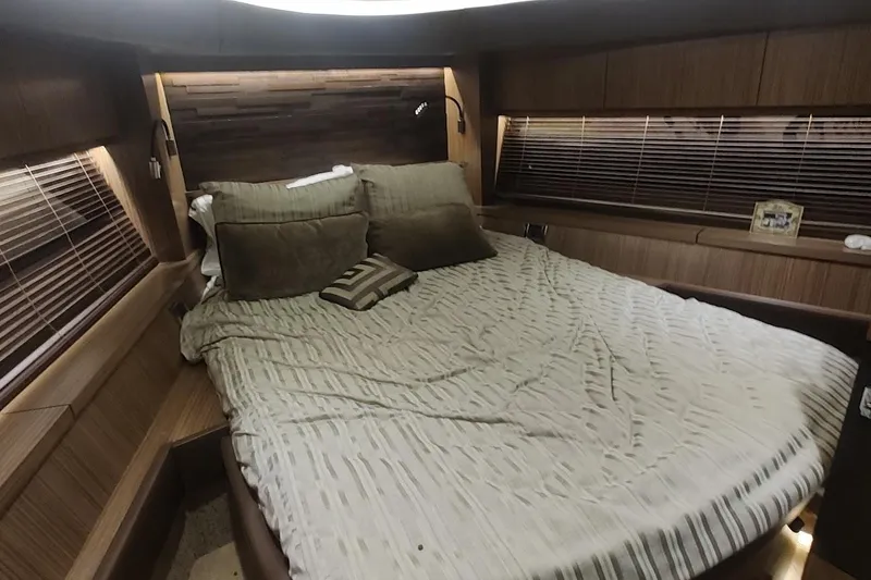 Slide: The Image of Luxurious 2016 Sea Ray L590 yacht bedroom with cozy bedding and elegant wood paneling. - 30