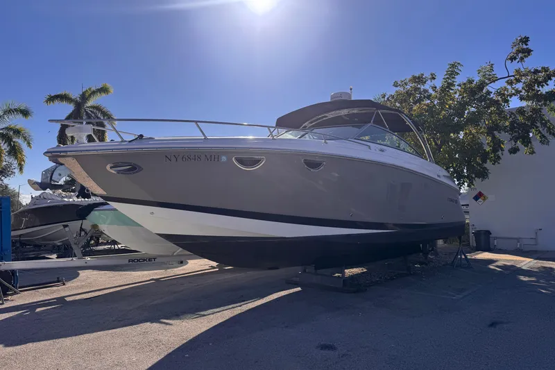 Slide: The Image of 2010 Cobalt 323 boat on trailer under clear blue sky with palm trees. - 2