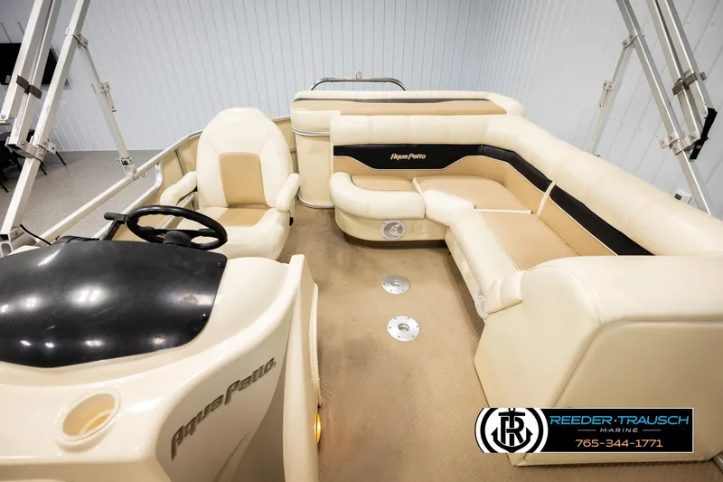 Slide: The Image of 2004 AquaPatio 220 RE boat interior with beige seating and steering console. - 14