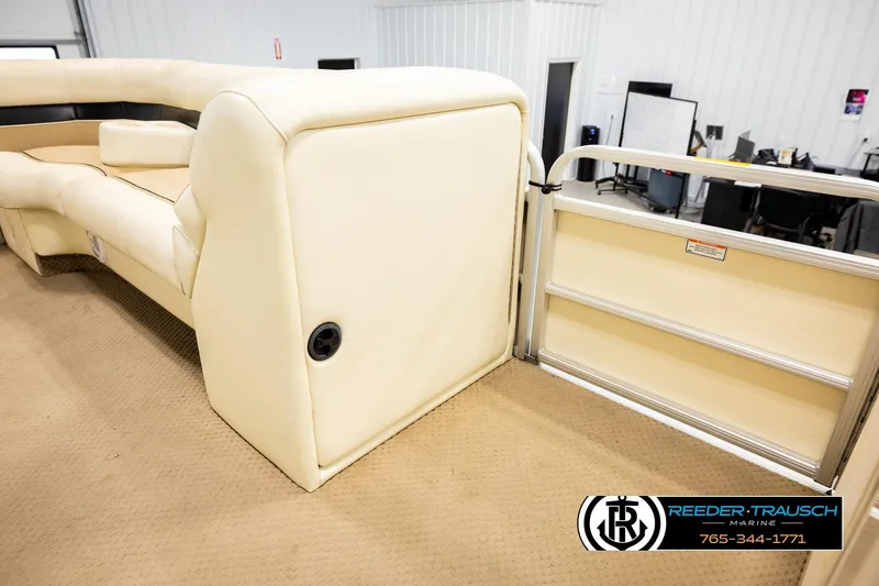 Slide: The Image of 2004 AquaPatio 220 RE boat interior with beige seating and gate, Reeder-Trausch Marine logo visible. - 22