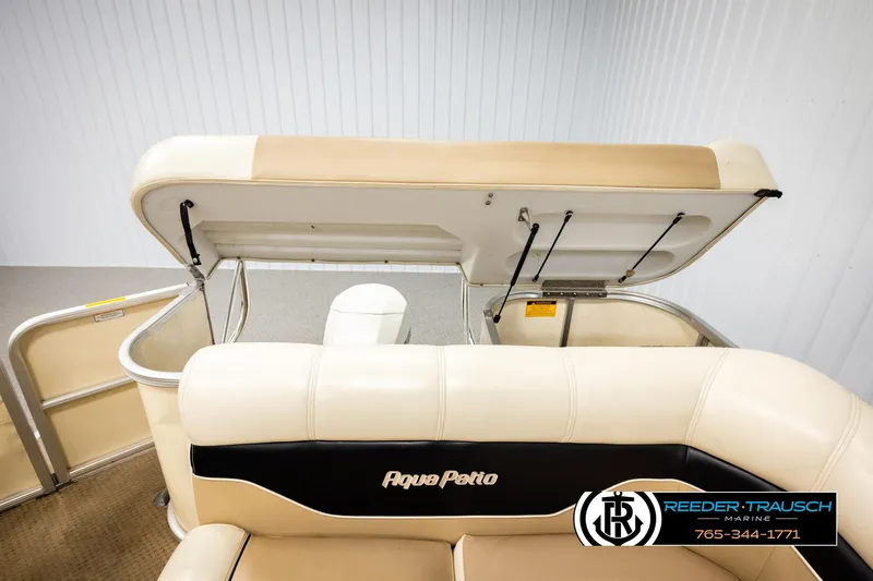 Slide: The Image of 2004 AquaPatio 220 RE boat interior with open storage compartment and beige seating. - 26