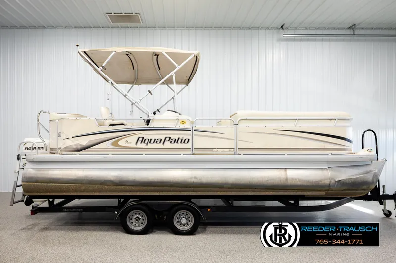 Slide: The Image of 2004 AquaPatio 220 RE pontoon boat with canopy, displayed indoors on a trailer. - 5