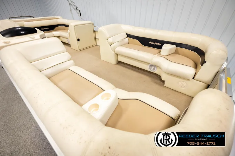 Slide: The Image of 2004 AquaPatio 220 RE boat interior with beige seating and cup holders. - 9