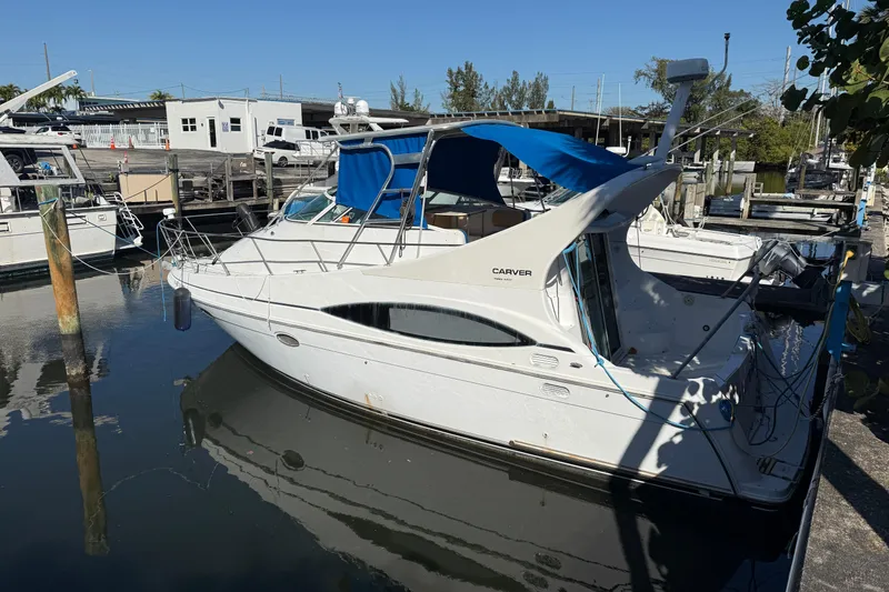 Slide: The Image of 2000 Carver 350 Mariner yacht docked at marina, featuring blue canopy and sleek design. - 2