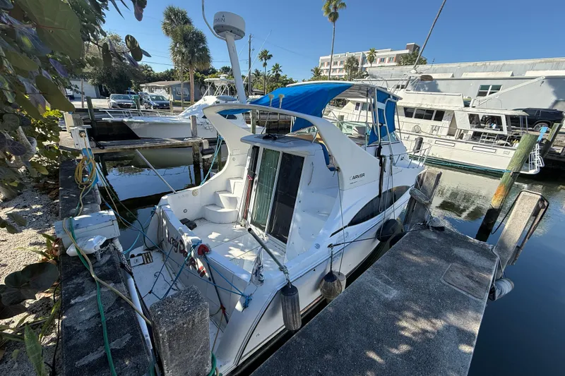 Slide: The Image of 2000 Carver 350 Mariner docked at marina with blue canopy and lush surroundings. - 4