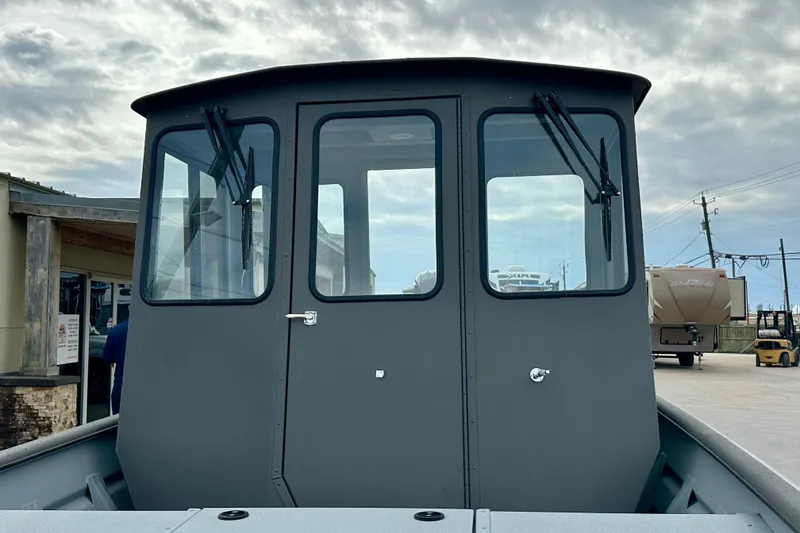 Slide: The Image of 2026 SeaArk 2472 CUB boat with enclosed cabin, docked under cloudy sky. - 16