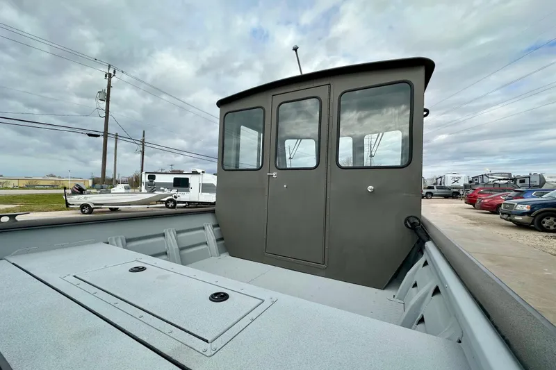 Slide: The Image of 2026 SeaArk 2472 CUB boat with cabin, parked outdoors under cloudy sky. - 18