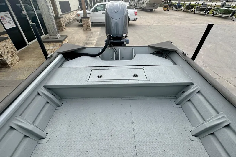 Slide: The Image of 2026 SeaArk 2472 CUB boat interior with motor, parked outdoors. - 19