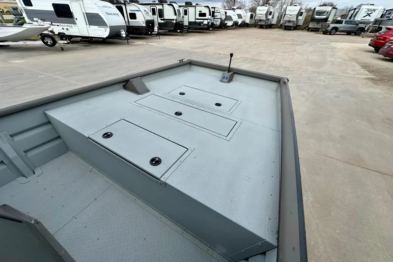 Slide: The Image of 2026 SeaArk 2472 CUB boat interior with storage compartments, parked near RVs. - 9