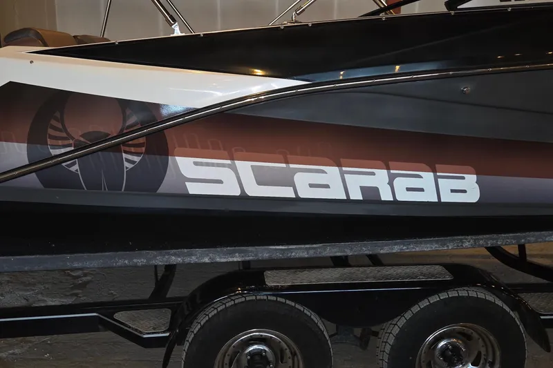 Slide: The Image of 2018 Scarab 255 boat on trailer, featuring bold logo and sleek design. - 2