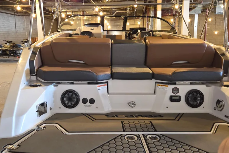Slide: The Image of 2018 Scarab 255 boat interior with brown seating and audio speakers in a warehouse setting. - 4