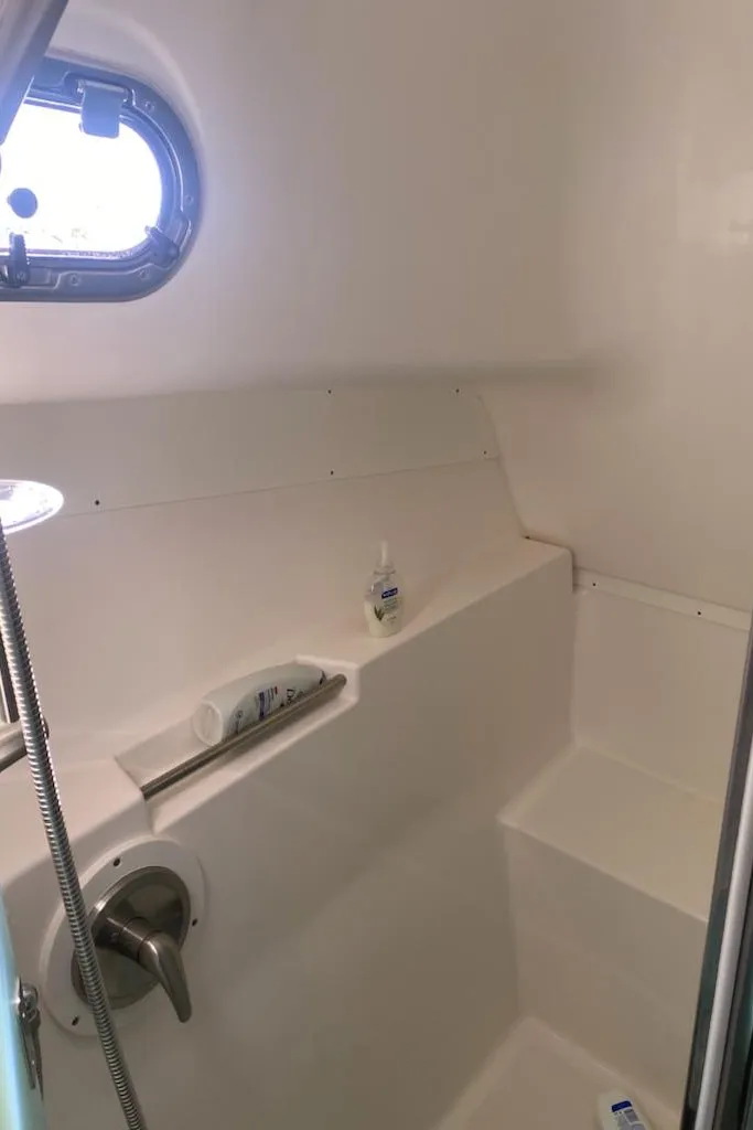 Slide: The Image of 2018 Pursuit OS 385 Offshore boat bathroom with porthole and shower amenities. - 14