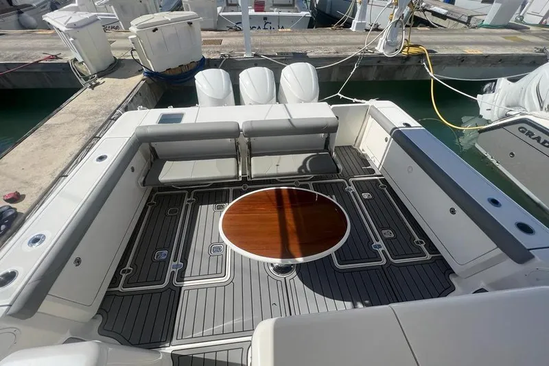 Slide: The Image of 2018 Pursuit OS 385 Offshore boat deck with seating and round table at marina. - 6
