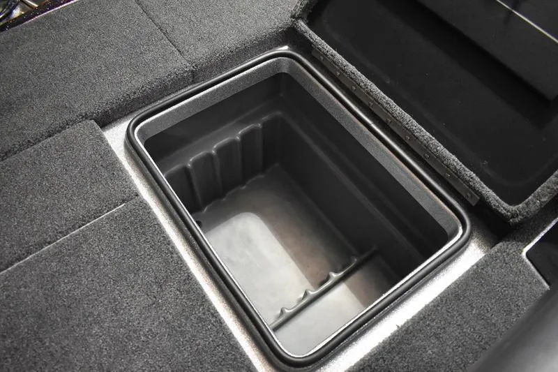 Slide: The Image of 2026 Triton 18 TrX boat storage compartment with open lid, featuring carpeted surroundings. - 13