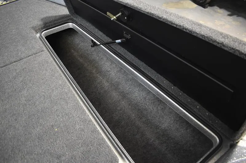 Slide: The Image of Open storage compartment in 2026 Triton 18 TrX boat, featuring carpeted interior. - 9